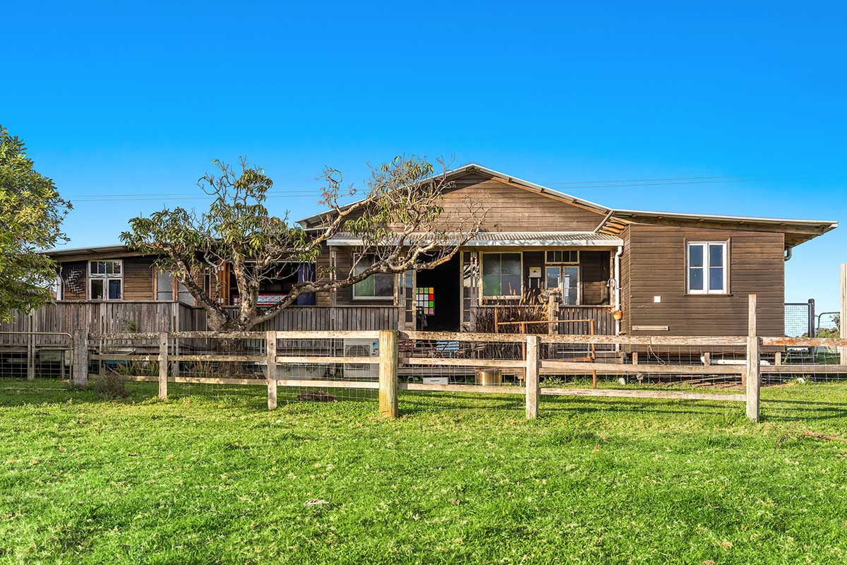 Middle Shed is a dark brown timber house with green pastures in the foreground